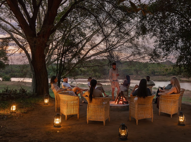A fireside gathering beneath the trees at twilight